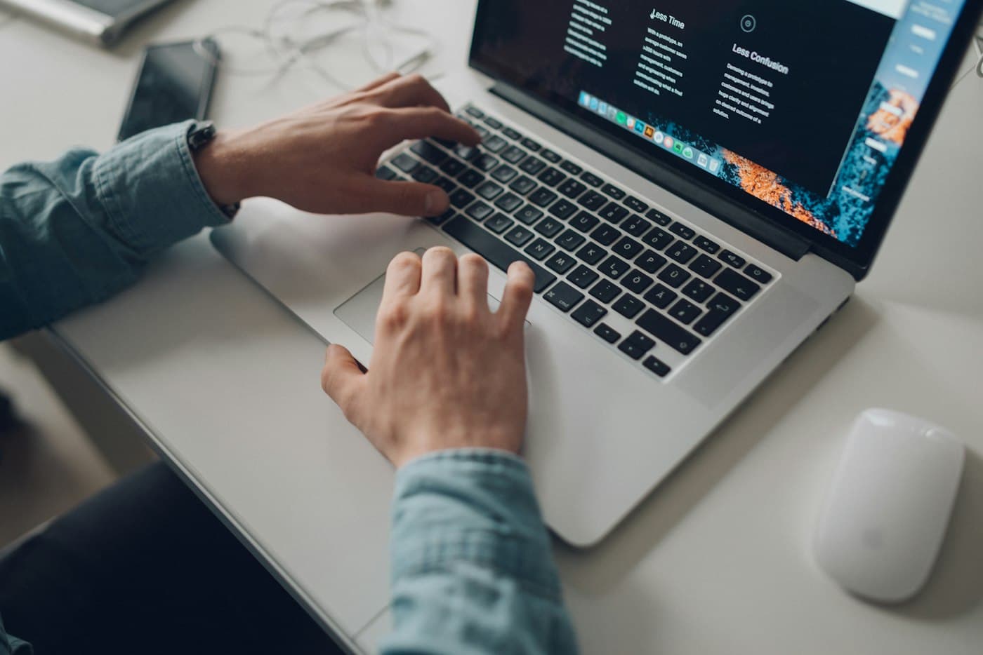 Hands typing on a laptop at a bright desk